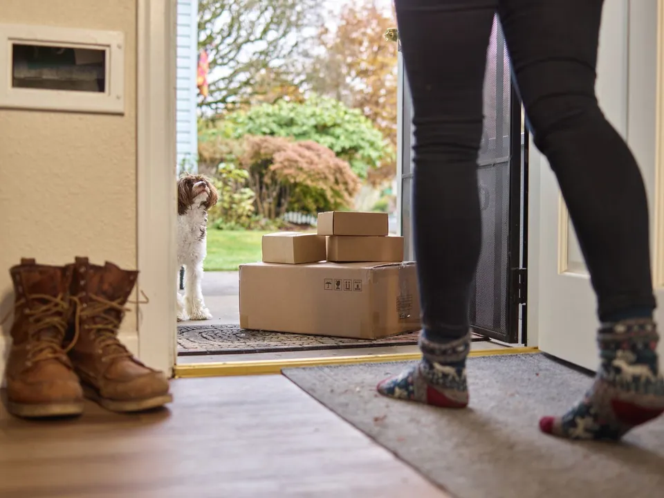 Delivered boxes stacked on a doormat outside an open front door