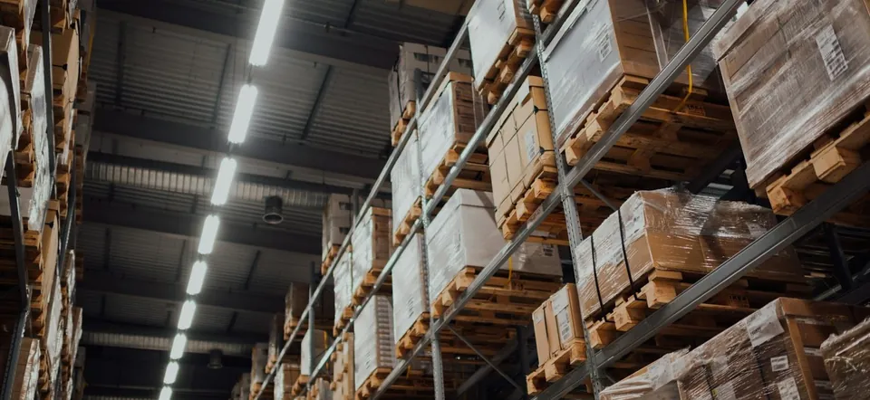 Tall warehouse racks of shrink-wrapped pallets and cartons
